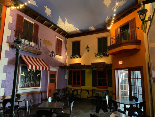 Colorful restaurant interior featuring purple and orange walls, decorative balconies, and cozy seating arrangements.