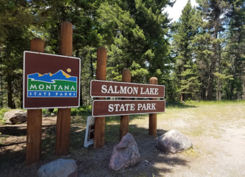 Sign for Salmon Lake State Park in Montana, surrounded by trees and natural scenery.
