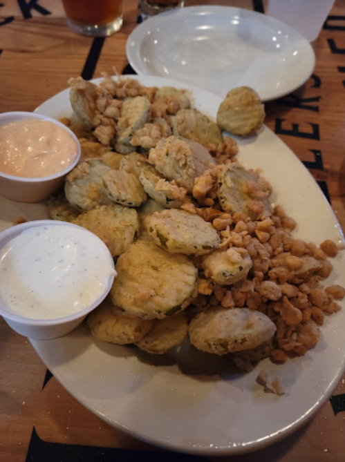 A plate of fried food featuring crispy bites, served with two dipping sauces in small cups.