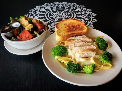 A plate of fettuccine with chicken and broccoli, served with a side salad and toasted bread.