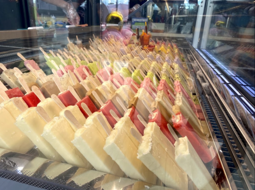 A display case filled with colorful popsicles on sticks, arranged in neat rows.
