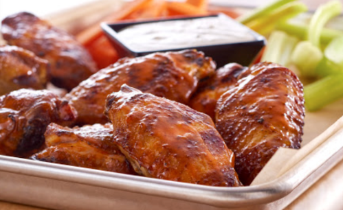 A platter of crispy chicken wings with celery, carrots, and a small bowl of dipping sauce.