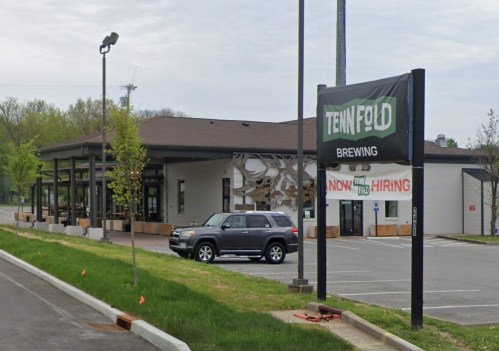 Exterior of Tenn Fold Brewing with a "Now Hiring" sign and a parked SUV in the lot.
