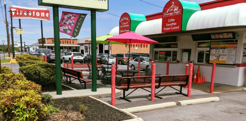 A colorful drive-thru with outdoor seating, umbrellas, and a Firestone sign in the background.