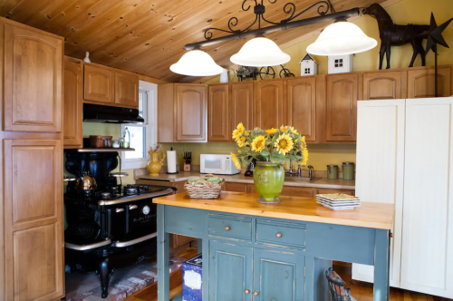 Cozy kitchen with wooden cabinets, a vintage stove, and a table adorned with sunflowers and decorative items.