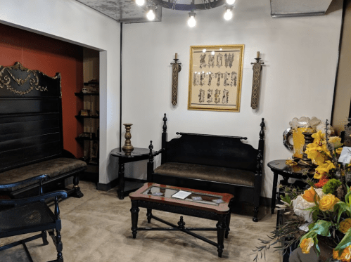 A cozy room with black furniture, a decorative wall art piece, and a floral arrangement on a table.