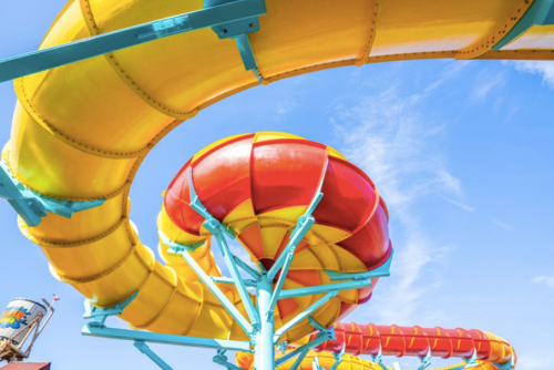 Colorful water slide twisting against a blue sky, featuring bright yellow, red, and blue sections.