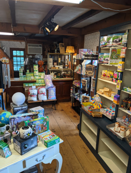 A cozy shop interior filled with various gifts, snacks, and souvenirs, featuring wooden floors and rustic decor.