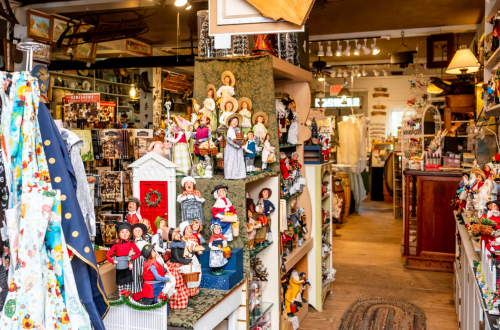 A charming shop interior filled with decorative dolls, crafts, and various handmade items on display.
