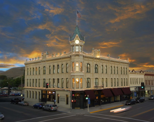 Historic building with a clock tower, adorned with lights, set against a dramatic sunset sky.