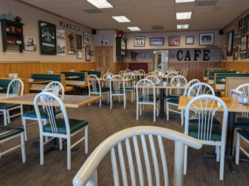 A cozy café interior with empty tables and chairs, wooden walls, and framed photos on the walls.