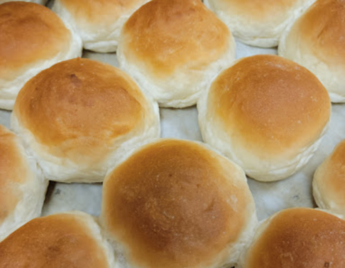 Freshly baked golden-brown dinner rolls arranged on a tray.