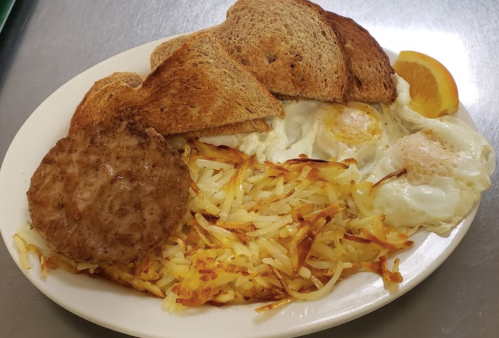 A plate of breakfast featuring toast, eggs, hash browns, a sausage patty, and a slice of orange.