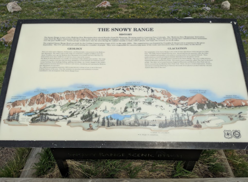 Sign detailing the Snowy Range's history, geology, and glaciation, with an illustrated mountain landscape.