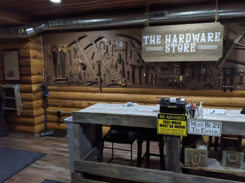 A rustic hardware store interior featuring a wooden counter and a wall adorned with various tools.