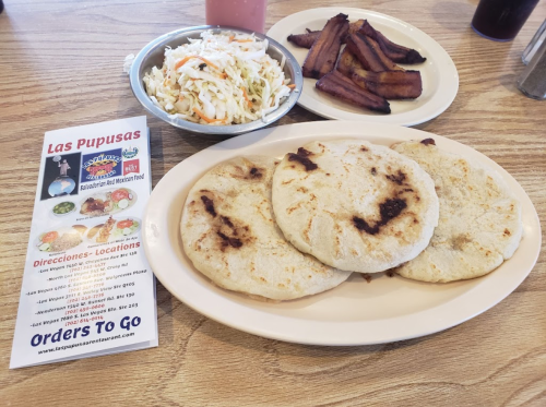 A plate with three pupusas, a side of coleslaw, and crispy bacon, alongside a menu for a Salvadoran restaurant.