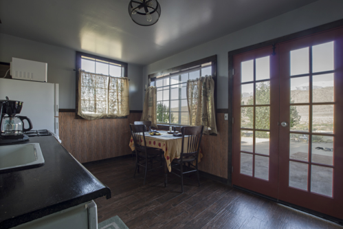 A cozy kitchen with a dining table, chairs, and large windows overlooking a scenic view.