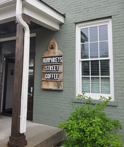 Sign for Humphreys Street Coffee on a green brick wall, next to a large window and a small bush.