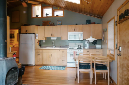 Cozy kitchen with wooden cabinets, a stove, and a dining table, featuring a warm, inviting atmosphere.