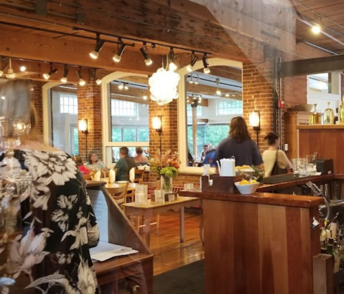 A cozy restaurant interior with wooden accents, tables, and patrons enjoying their meals in a warm atmosphere.