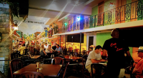 A vibrant restaurant interior with colorful murals, wooden tables, and patrons enjoying their meals.