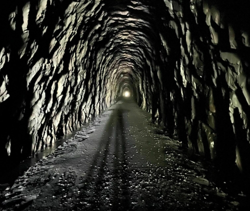 A dark, rocky tunnel with a faint light at the end, creating a mysterious and eerie atmosphere.