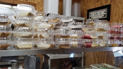 A display of stacked plastic containers filled with various desserts in a bakery setting.
