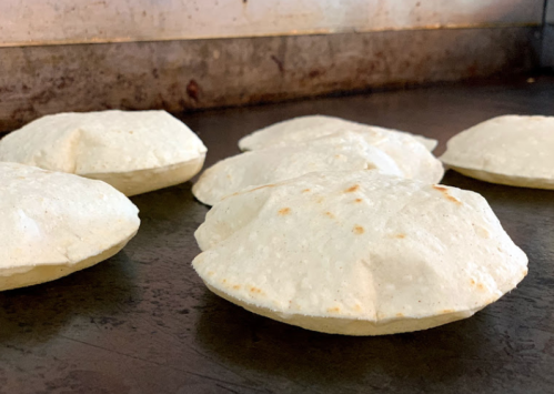 A close-up of several puffed tortillas resting on a flat surface, showcasing their round, golden-brown edges.
