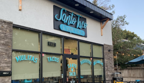 Exterior of Santo Taco Taqueria, featuring large windows and a sign with the restaurant's name in blue lettering.