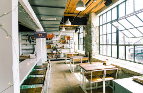Bright, modern restaurant interior with wooden tables, large windows, and a cozy atmosphere.