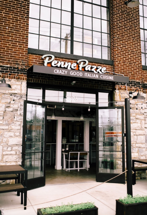 Exterior of Penne Pazze restaurant, featuring a sign that reads "Crazy Good Italian Cuisine" and large glass doors.