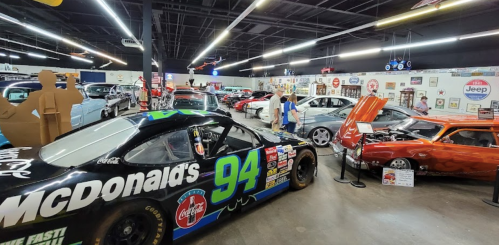 A vibrant car museum featuring classic cars and a McDonald's-themed race car in the foreground.
