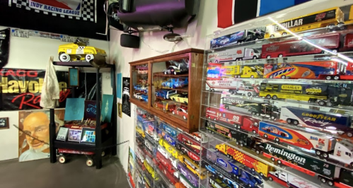 A room filled with model cars and racing memorabilia, featuring a display case and various racing-themed decorations.
