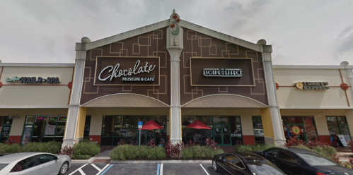 Exterior view of a building featuring the Chocolate Museum & Café, with outdoor seating and a modern architectural design.