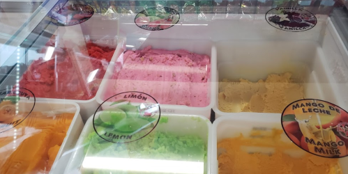 A display of colorful ice cream flavors in containers, labeled with names like lemon, mango, and strawberry.