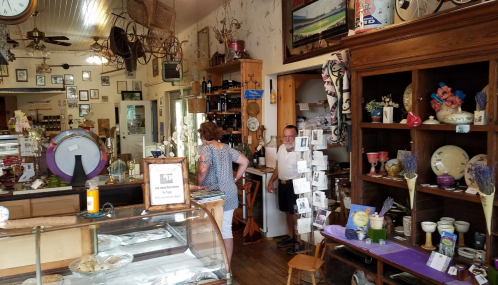A cozy shop interior filled with vintage items, shelves, and customers browsing among various decorations and antiques.