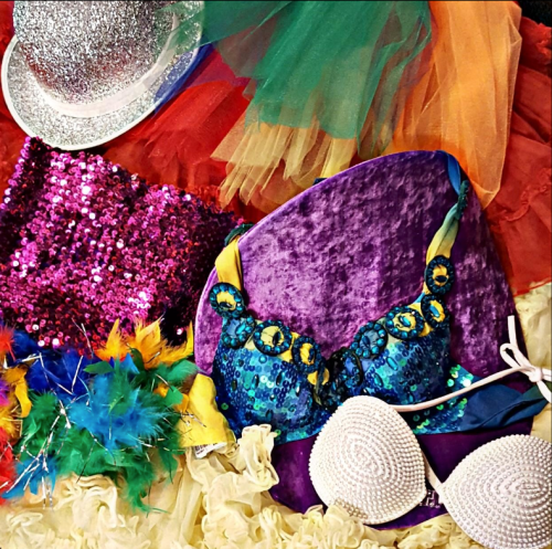A colorful assortment of costumes, including sequined bras, feathers, and vibrant fabrics.