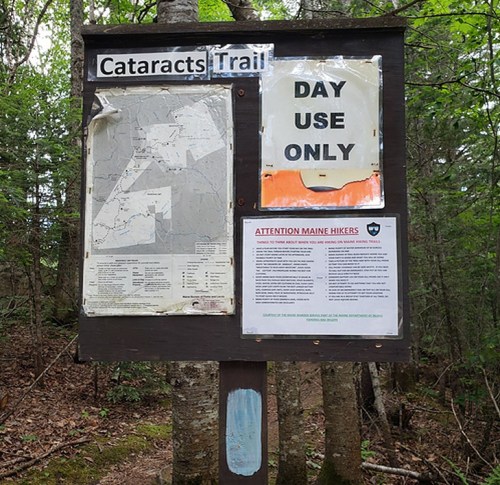 Signpost for Cataracts Trail featuring a map, "Day Use Only" notice, and hiker guidelines in a wooded area.