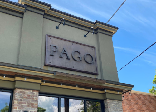 Sign for "PAGO" on a building exterior, with a clear blue sky in the background.
