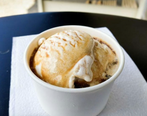 A cup of ice cream with a creamy swirl on top, placed on a napkin on a table.