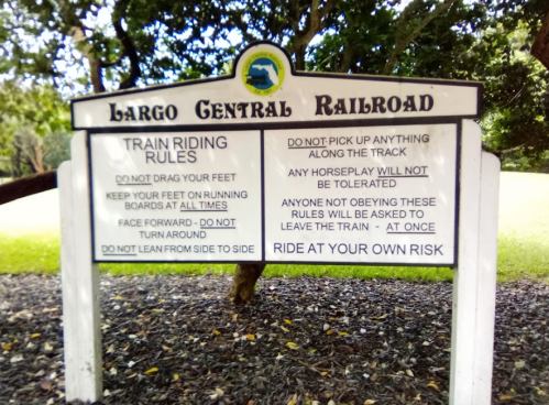 Sign with train riding rules for Largo Central Railroad, including safety instructions and warnings for riders.