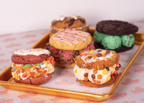 A tray of colorful cookie sandwiches filled with various toppings and frostings, showcasing a variety of flavors.