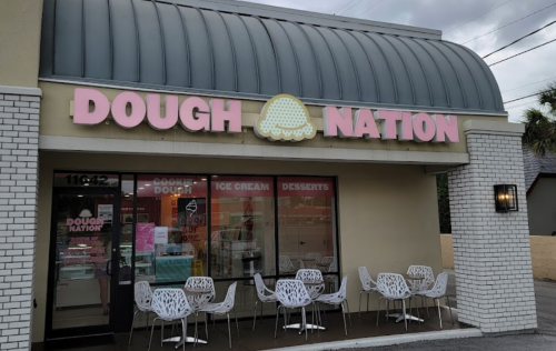 Exterior of a shop named "Dough Nation," featuring a pink sign, outdoor seating, and a modern design.
