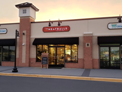 Exterior of a restaurant called "Two Meatballs Italian Grill," with a sign and large windows, at sunset.