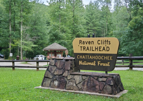 Sign for Raven Cliffs Trailhead in Chattahoochee National Forest, surrounded by lush green trees.