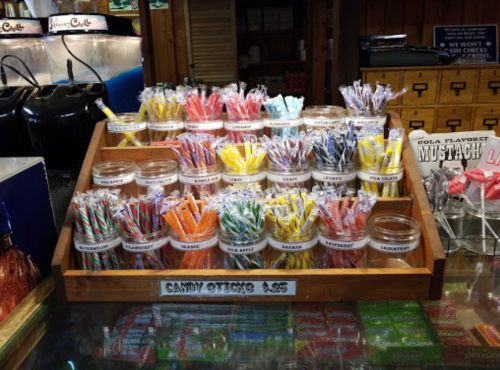 A wooden display filled with colorful candy sticks in various flavors, labeled and neatly arranged.