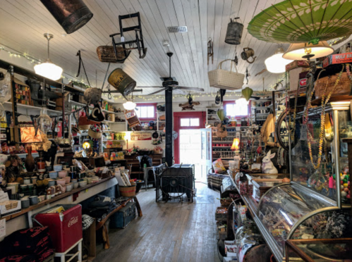 A cozy vintage shop filled with eclectic items, including baskets, decor, and antiques, under warm lighting.