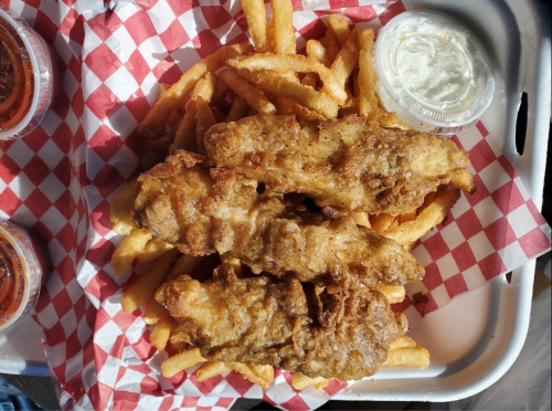 A tray of golden fried fish fillets served with crispy French fries and dipping sauces in containers.