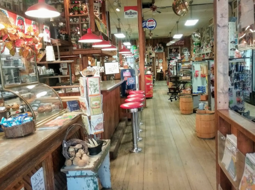 A vintage store interior with wooden floors, red stools, and various nostalgic items displayed on shelves.