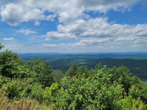 A panoramic view of lush green mountains under a partly cloudy blue sky.